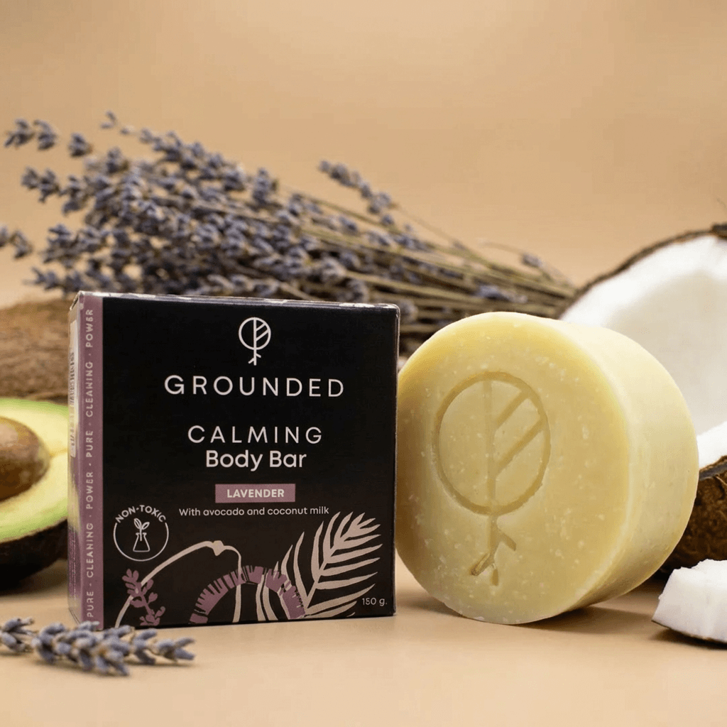 Grounded Calming Body Bar with packaging, surrounded by lavender and coconuts on a beige background