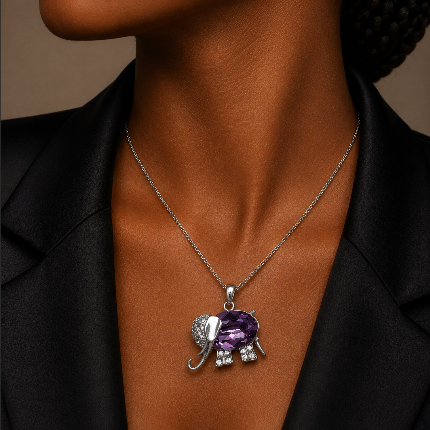 Necklace with an elephant pendant featuring a purple gemstone on a person wearing a black outfit.
