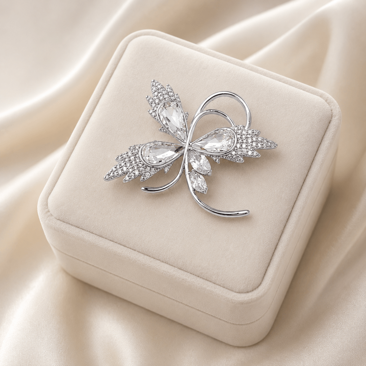 Silver butterfly-shaped brooch on a beige jewelry box with a soft beige fabric background