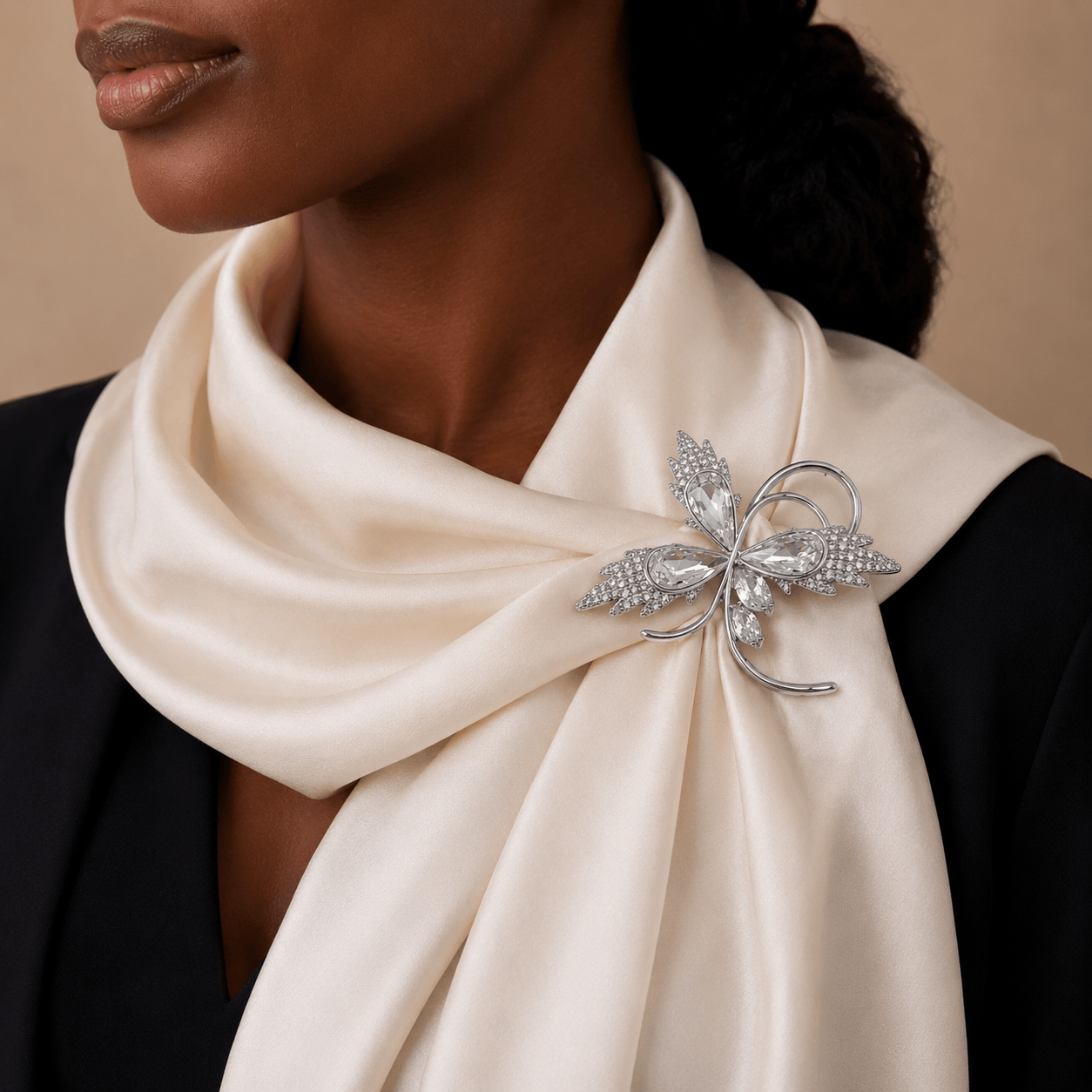 Close-up of a person wearing a white scarf with a decorative brooch, against a neutral background.